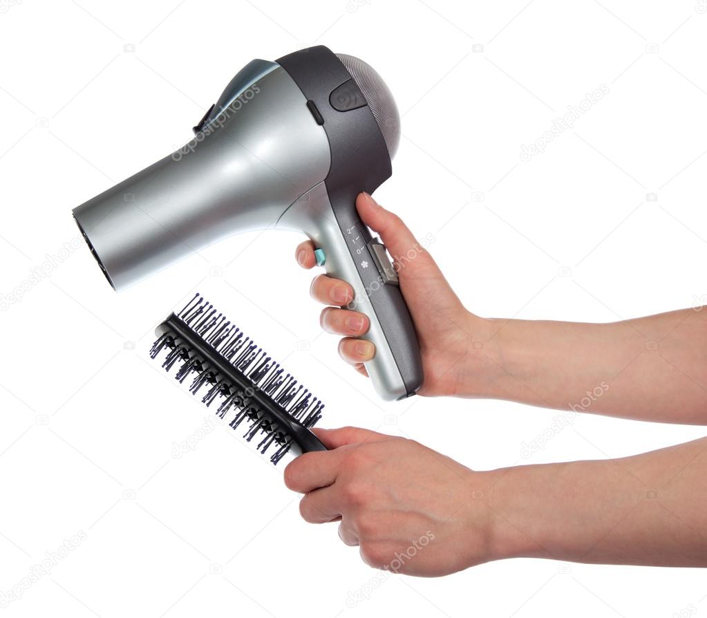 The female hands holding the hair dryer and a hairbrush, isolated on white