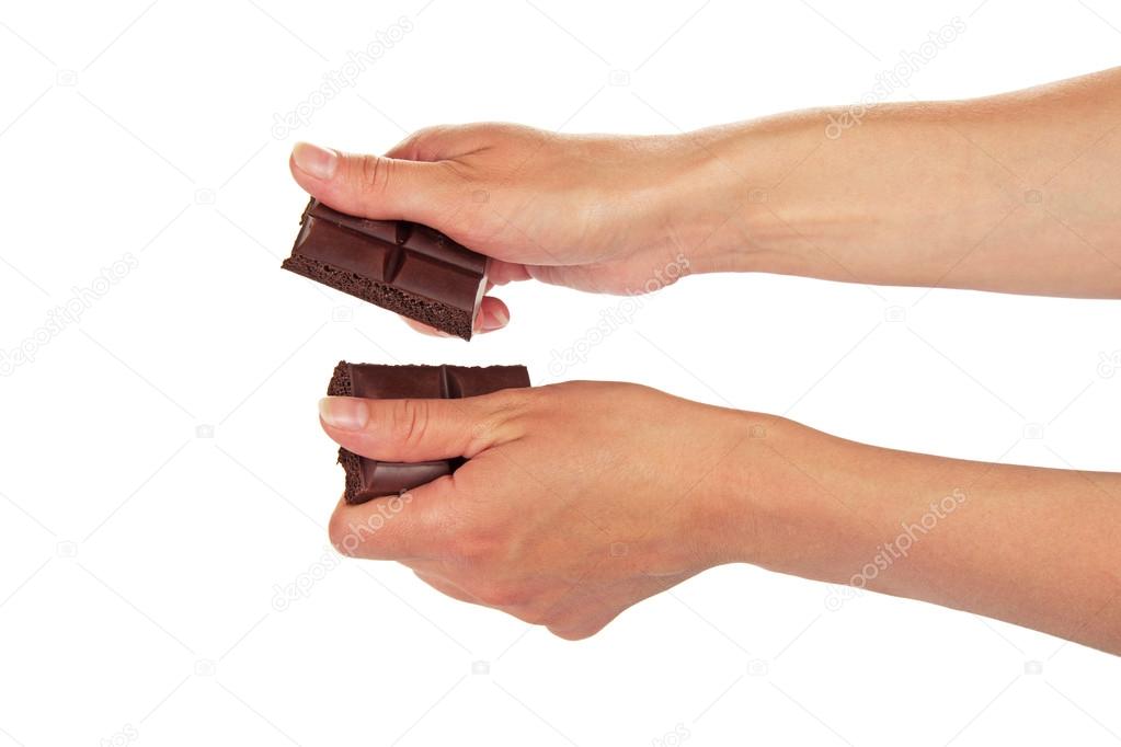 Female hands break a tile of the black chocolate, isolated on white