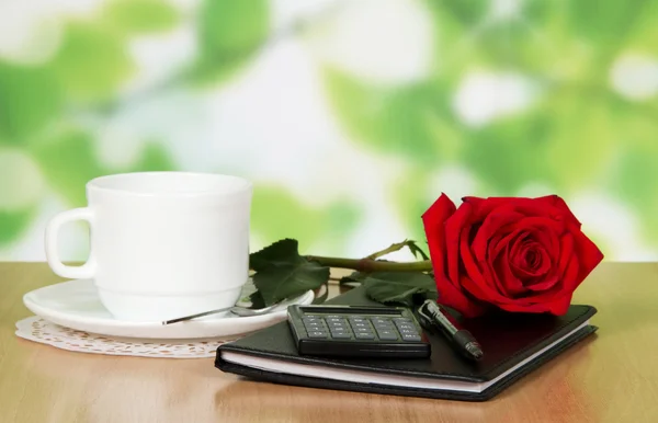 Table in cafe with a cup of coffee, rose and notebook — Stock Photo, Image