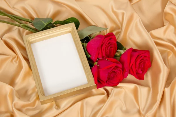 Empty photoframe with a bouquet of red roses — Stock Photo, Image