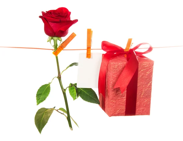 Роза, открытка и подарок висят на веревке — стоковое фото
