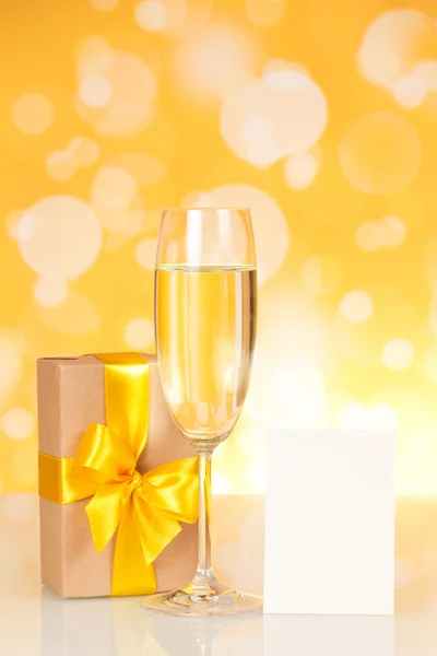 Glass with champagne, gift and empty card — Stock Photo, Image