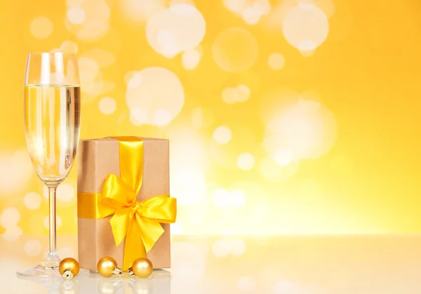 Glass with champagne and a gift — Stock Photo, Image