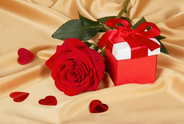 Красные розы и подарочная коробка на золотой ткани — стоковое фото