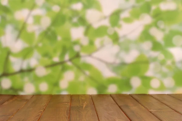 Lege houten dektafel met loof bokeh achtergrond — Stockfoto