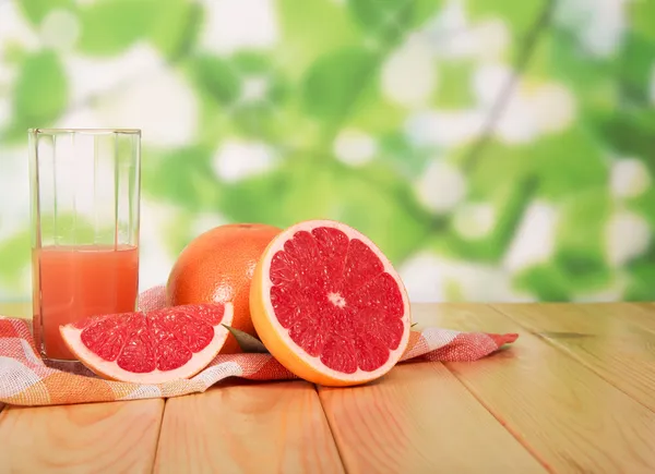 Glas van grapefruitsap en gesneden?? op tafel in tuin — Stockfoto