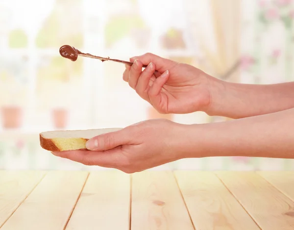 Hands spread chocolate paste on toast — Stock Photo, Image