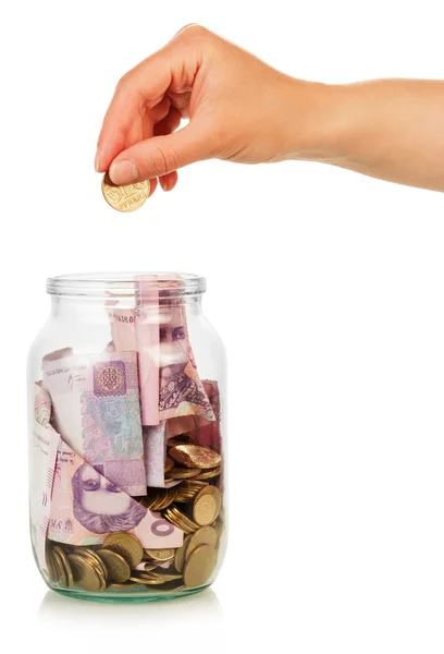 Hand puts coin in jar — Stock Photo, Image