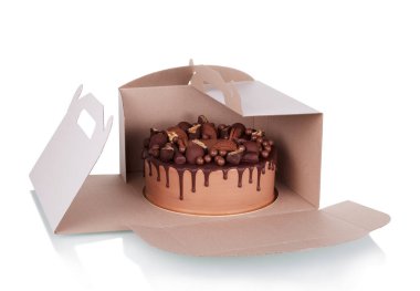 Beyaz arka planda izole edilmiş karton kutudaki şekerlerle süslenmiş çikolatalı pasta.