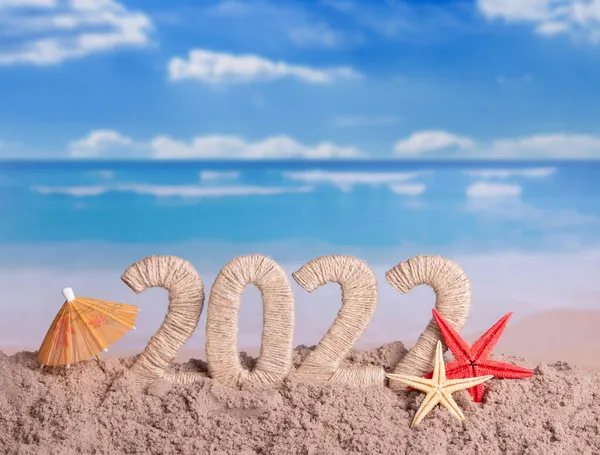 ビーチで新年 海を背景にした砂 ヒトデ 傘の銘文2022 — ストック写真