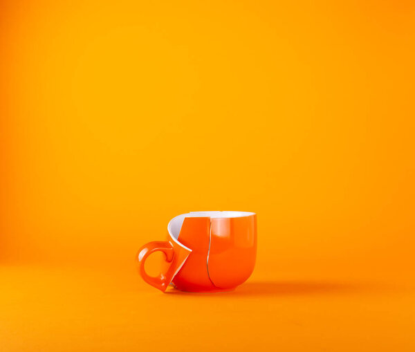 Broken large cup for tea and drinks on an orange background