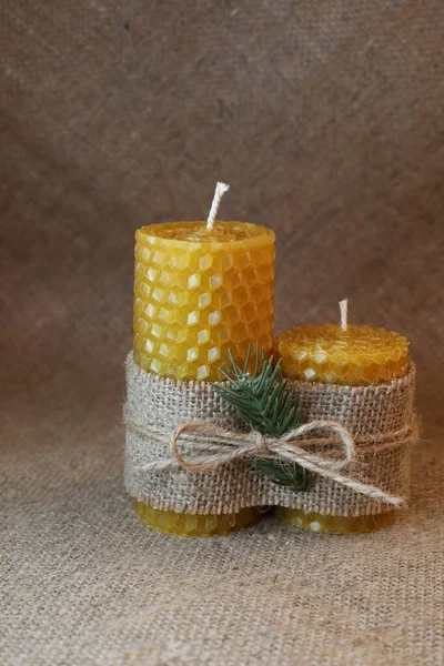 Handmade beeswax candles on the rustic background. Two natural bio wax candles as a decoration for home interior.