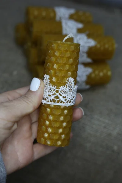 Yellow beeswax candle on the rustic linen background. Natural bio wax candles as a decoration for home interior.