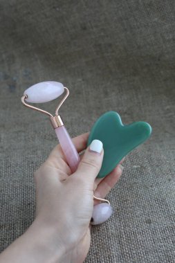 Yeşil taş guasha ve pembe yüz silindiri kırsal alanda. Cilt bakımı kavramı.