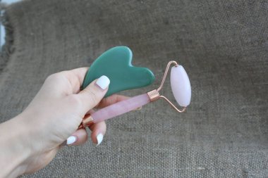 Yeşil taş guasha ve pembe yüz silindiri kırsal alanda. Cilt bakımı kavramı.