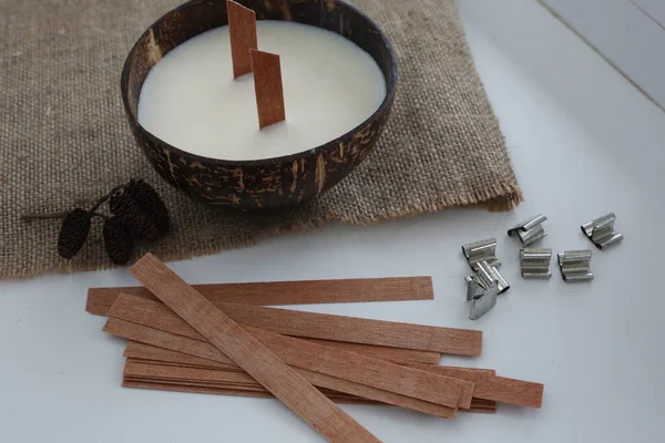 Handmade soy wax candle in coconut shell on white background.