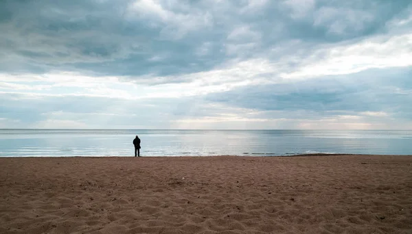 Osoba Stojąca Plaży Otoczona Morzem Pod Chmurnym Niebem — Zdjęcie stockowe