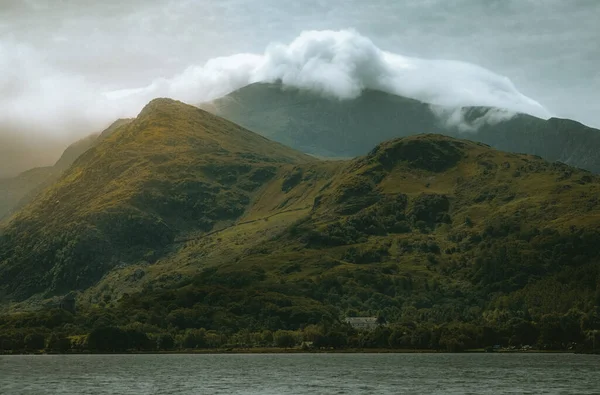 水の近くの雲に覆われた丘の信じられないほどの景色のクローズアップショット — ストック写真