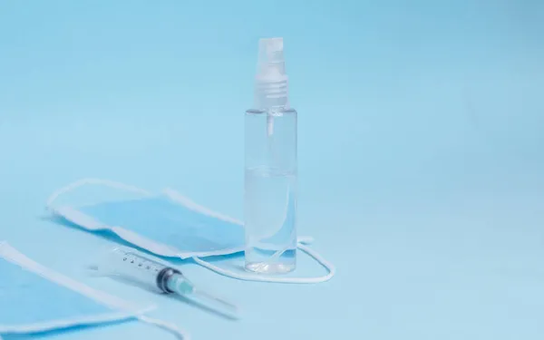 Een Close Shot Van Wegwerpgezichtsmaskers Injectiespuiten Handreiniger Een Lichtblauw Oppervlak — Stockfoto