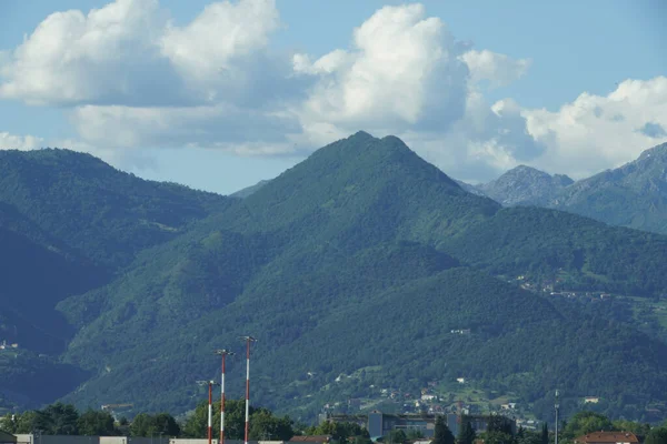 Kasabayı Çevreleyen Kabarık Bulutlu Büyük Yeşil Dağlar — Stok fotoğraf