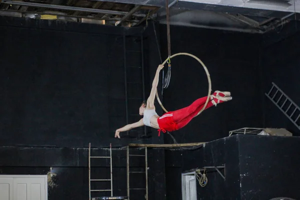 A young female aerial acrobat practicing on a hoop