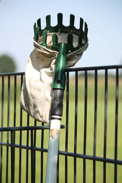 A vertical shot of a fruit picker on the background of a metal fence.
