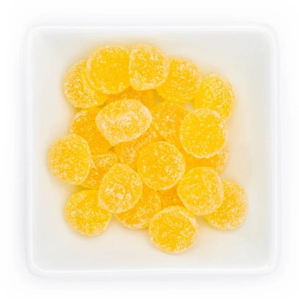 A top view of yellow gum drops in a white bowl