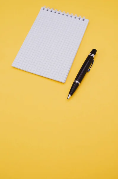 コピースペースのある黄色の表面に黒漆の高級ペンと紙ブロック — ストック写真