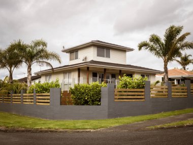 AUCKLAND, NEW ZEALAND - Sep 19, 2021: Typical New Zealand suburban house with palm trees. Cloudy day. Auckland, New Zealand - September 19, 2021 clipart