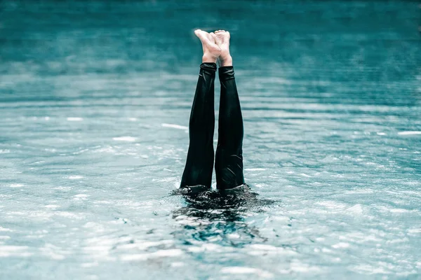 A shot of a person underwater with their lower body looking up out of it