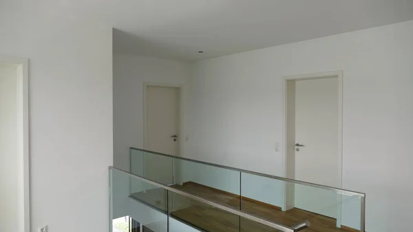 A white clean corridor of a modern apartment building with a glass fence