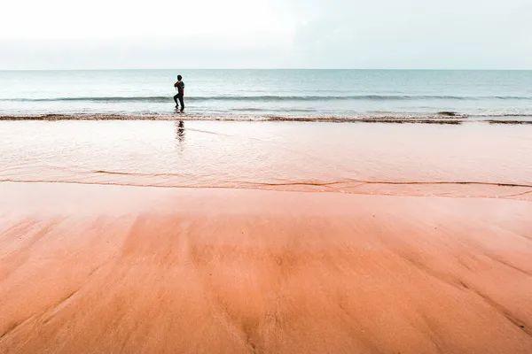 Strzał Młodego Chłopca Stojącego Wybrzeżu Umytego Falami Piaszczystej Plaży — Zdjęcie stockowe
