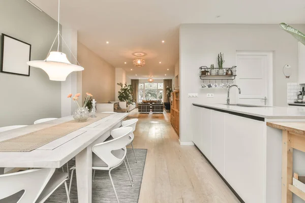 An interior shot of a dining room table next to a kitchen in a comfortable house