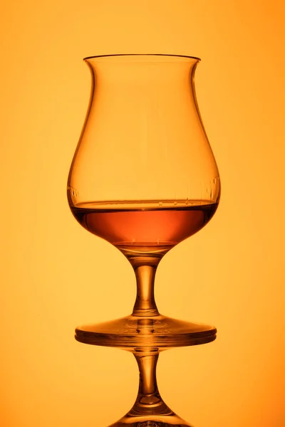 黄色の背景にガラスの中のウイスキーの垂直ショット — ストック写真