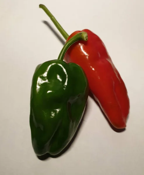 Disparo Vertical Pimiento Rojo Verde Sobre Una Superficie Blanca —  Fotos de Stock