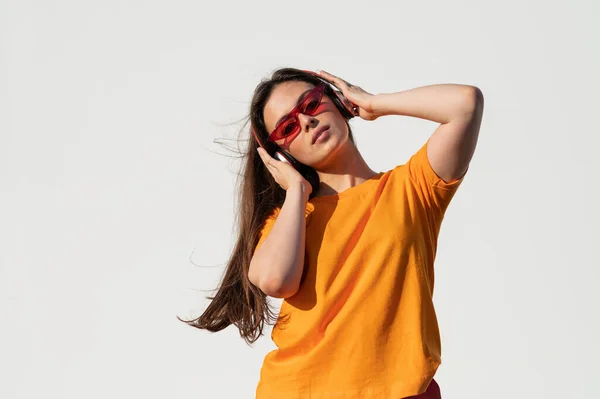 Uma Jovem Mulher Caucasiana Uma Camiseta Laranja Óculos Vermelhos Ouvindo — Fotografia de Stock