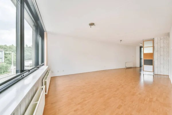 窓の横に白い壁と木製の床のある空の部屋のインテリアショット — ストック写真