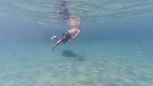 ギリシャのエーゲ海でカメラを持ちながらシュノーケリングをする男 — ストック写真