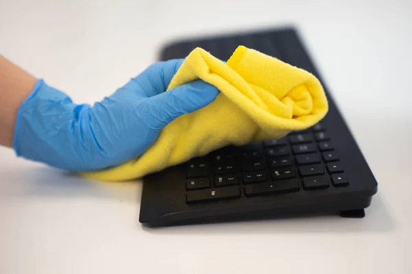 Person cleaning keyboard with a yellow microfiber cloth