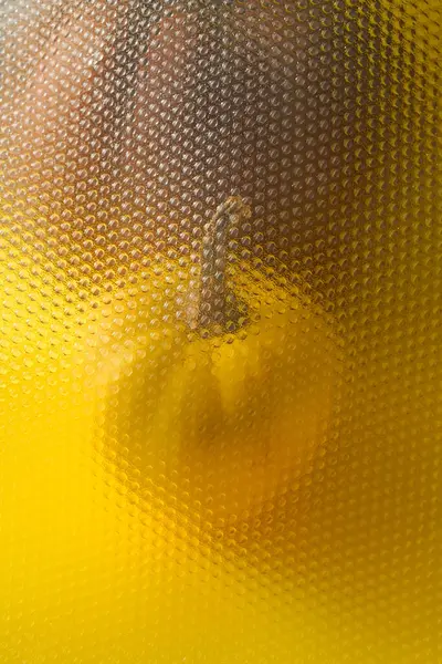万圣节前夕 在玻璃杯后面的一个黄色表面上垂直拍摄的南瓜 — 图库照片
