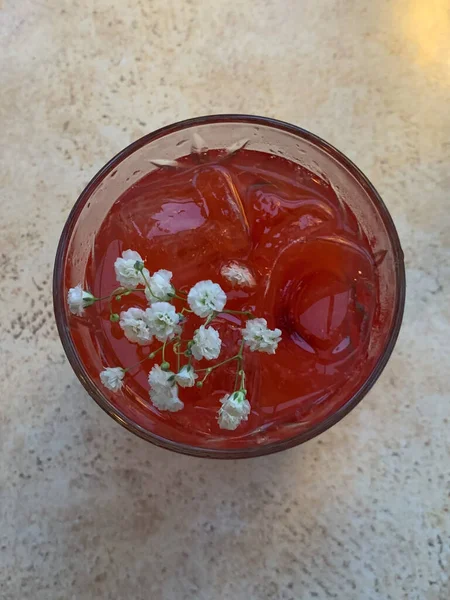 Eine Vertikale Aufnahme Eines Glases Saft Mit Eis Und Blumen — Stockfoto