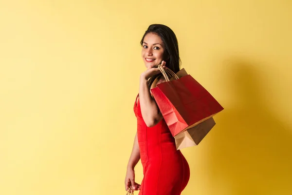Szczęśliwa Latynoska Czerwonej Sukience Trzyma Torby Zakupy Odizolowanym Żółtym Tle — Zdjęcie stockowe