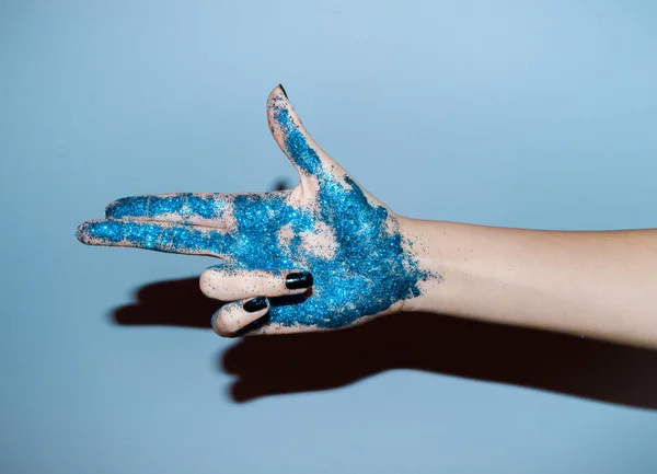Χέρι Ενός Κοριτσιού Γεμάτο Γκλίτερ Σχήμα Όπλου Μπλε Φόντο — Φωτογραφία Αρχείου