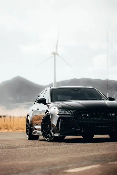 Carro Preto Luxo Estrada Dia Ensolarado Com Uma Turbina Eólica — Fotografia de Stock