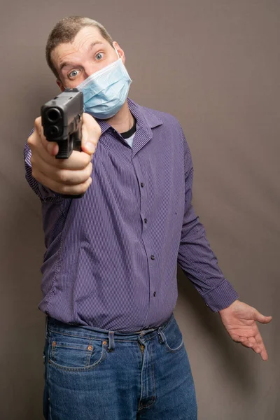 Pionowe Ujęcie Młodego Białego Mężczyzny Masce Medycznej Trzymającego Broń — Zdjęcie stockowe