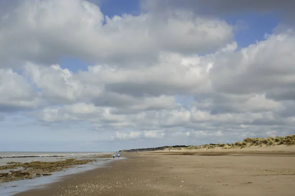 Pejzaż Plaży Kilkoma Spacerującymi Ludźmi Szerokim Błękitnym Niebem Białymi Bawełnianymi — Zdjęcie stockowe