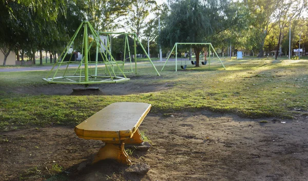 背景に遊具のある公園のベンチの上で — ストック写真