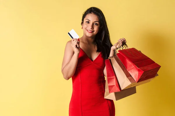 Szczęśliwa Latynoska Czerwonej Sukience Kartą Kredytową Torbami Zakupy Odizolowanym Żółtym — Zdjęcie stockowe