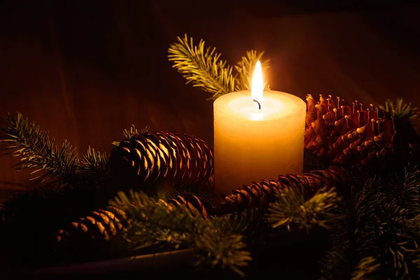 Detailní Záběr Zapálené Svíčky Obklopené Borovými Kužely Tmavém Vánočním Prostředí — Stock fotografie