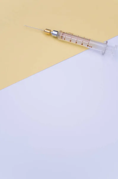 Separat Injektionsspruta Gult Och Vitt Papper Bakgrund Med Textutrymme — Stockfoto